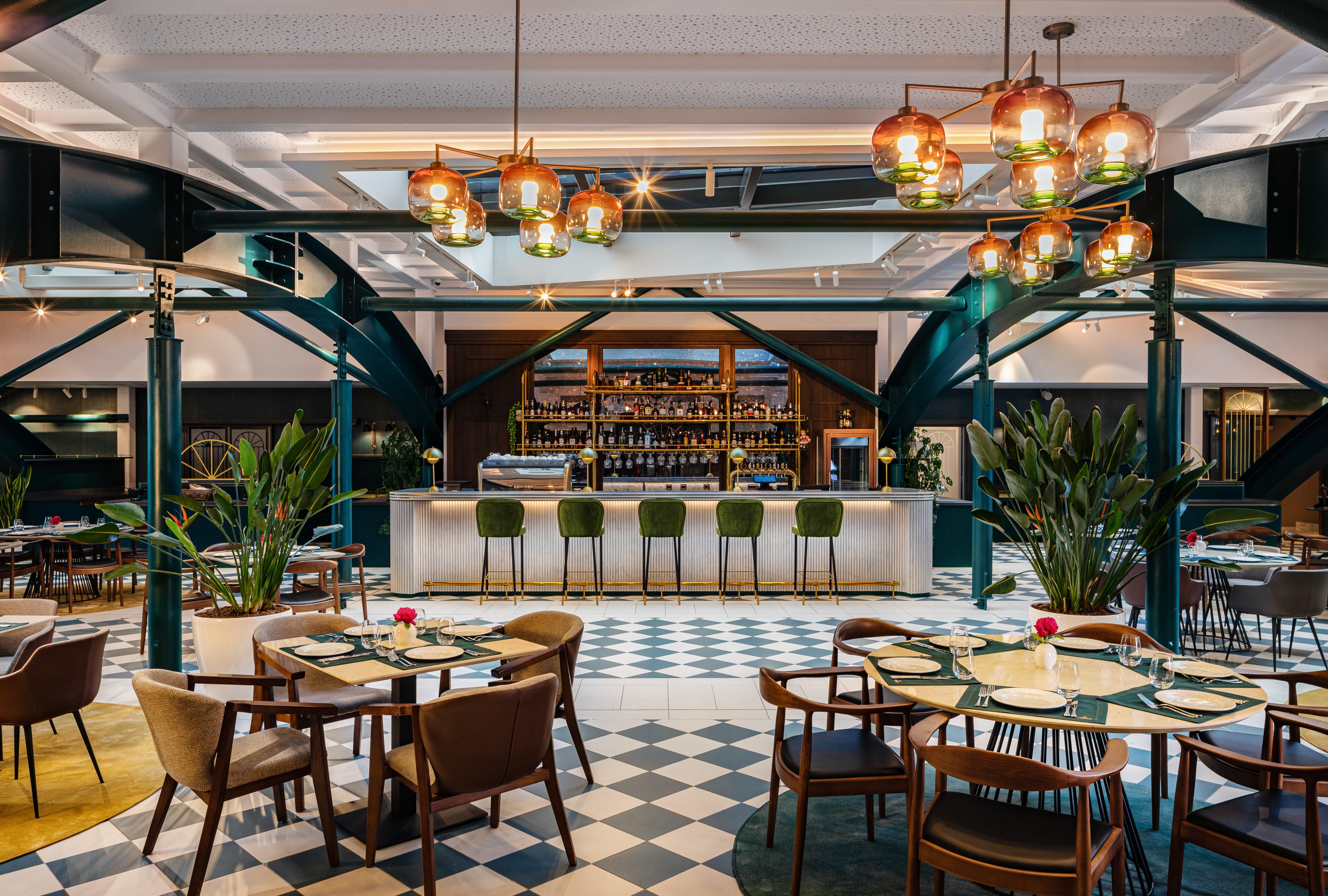 Grand Hotel Millennium Sófia Exterior foto The photo showcases a stylish restaurant interior. There are several tables set with chairs arranged around them, featuring a mix of styles. In the background, a sleek bar counter is visible, stocked with various bottles. The bar is complemented by e
