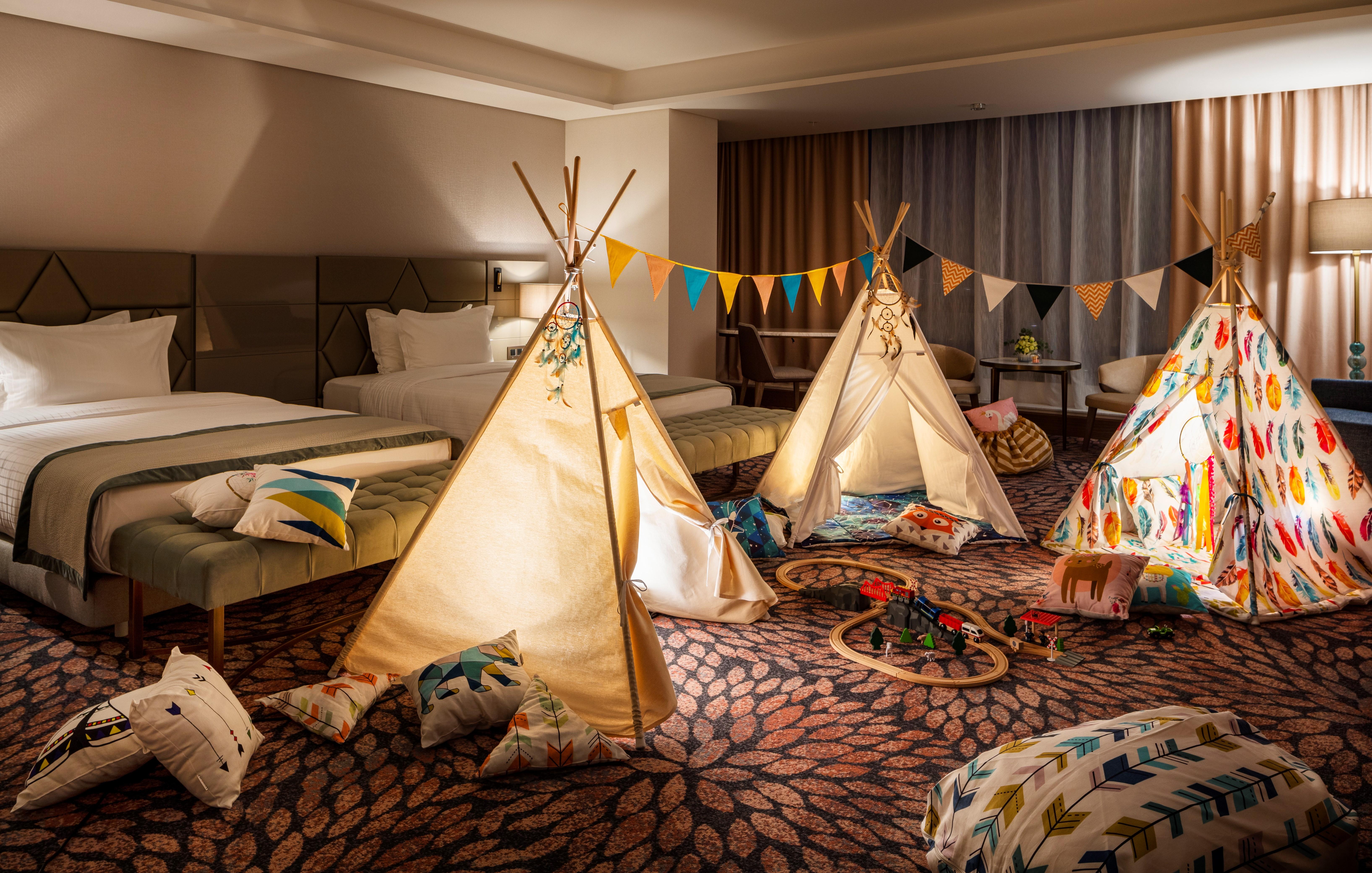 Grand Hotel Millennium Sófia Exterior foto The photo shows a cozy room featuring three children's teepees made of fabric, arranged in a playful manner. The teepees are decorated with colorful patterns and surrounded by various cushions and pillows scattered on the floor. There are also decora